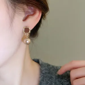 Vintage champagne pearl drop earrings featuring square gold studs on model