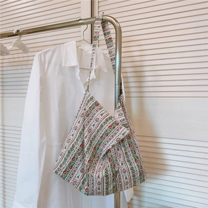 Sac hobo en toile de coton à fleurs rouges et vertes suspendu à un portant à linge