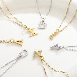 Flat lay of gold and silver titanium steel necklaces with diverse alphabet pendants