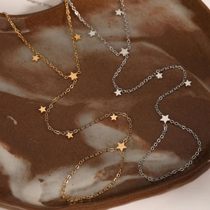 Chic gold and silver star chain bracelets displayed on a minimalist textured plate