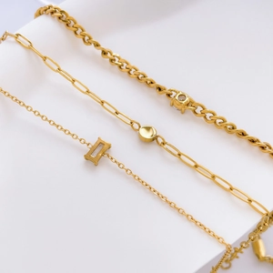 Three gold titanium steel bracelets featuring square and round gemstones on a white background