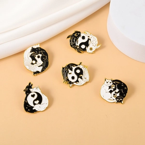 Detailed view of five black and white enamel animal pins with gold trim on silk background