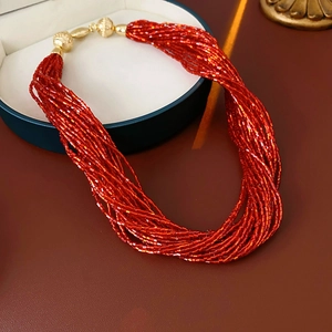 Dettaglio della collana di perline rosse multistrato con chiusura magnetica dorata su pelle