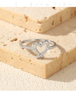 Detail of silver heart ring with small crystals placed on a natural beige stone