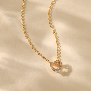 Macro detail of 18K gold plated heart pendant with pavé cubic zirconia and central stone