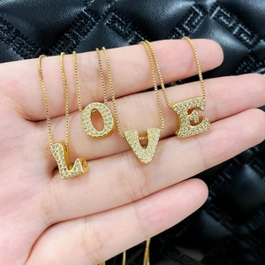 Gold plated initial necklaces set with zircon stones spelling LOVE on a luxury bag