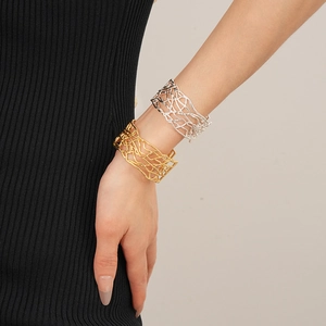 Gros plan de bracelets manchettes évidés en or et argent portés par un mannequin