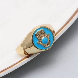 Close-up of golden Hamsa ring with sky blue enamel and sparkling crystal accents
