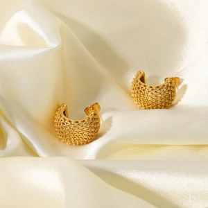 Detailed view of gold grid earrings with mesh texture on elegant beige silk fabric