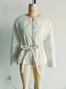 Detail view of cream quilted jacket with zip closure and adjustable waist belt