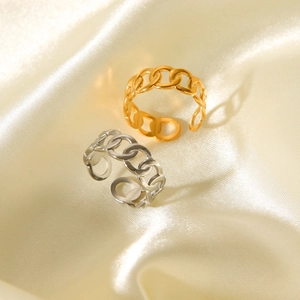 Macro shot of Cuban link chain rings in gold and silver finish on soft silk fabric