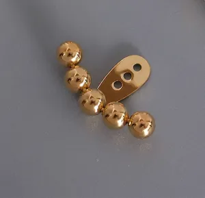 Macro shot of gold titanium steel multi-bead earrings with a polished mirror finish