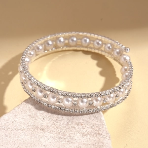 Macro detail of multi-layered pearl and rhinestone spiral bracelet on stone base