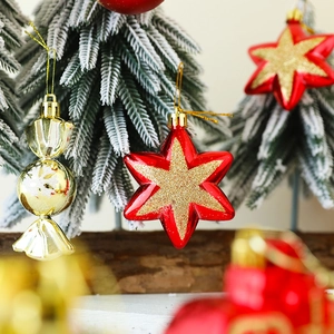 Close-up of red and gold glittery star and candy ornaments on a mini Christmas tree