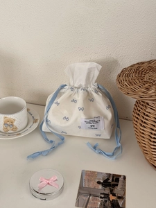 Detail view of a fabric tissue box bag with blue bows and decorative lifestyle props