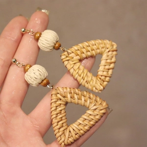 Detailed view of bohemian hand-woven triangle drop earrings with natural wood beads