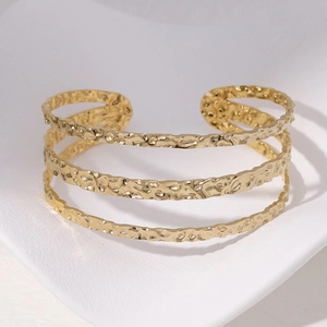 Detailaufnahme eines goldenen Armreifs mit unregelmäßiger Hammerschlagstruktur im Lagenlook