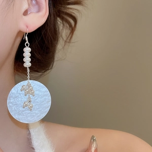 Detailed view of long vintage drop earrings with white pearls and hammered silver disc