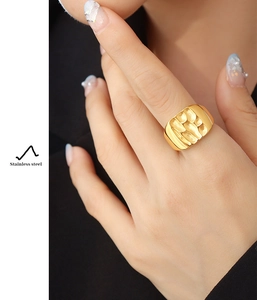 Close-up of gold-plated stainless steel wide ring with irregular texture on model hand
