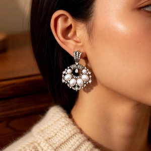 Detailed close-up of vintage gold earrings with pearls and crystals on a model