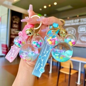 Detail of pink and blue glowing liquid candy keychains with golden bells and wristbands