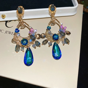 Macro shot of gold floral earrings featuring teardrop sapphire and crystal beads