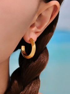 Close-up of model wearing polished C-shaped 18k gold plated hoop earrings in metal