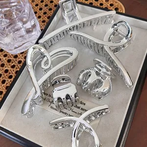 Polished silver metal hair claw set in various shapes displayed in a minimalist jewelry box