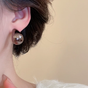 Close-up of minimalist teardrop earrings in polished silver metal worn by a model
