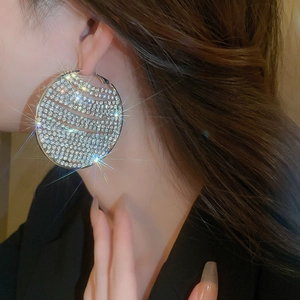 Detailed view of silver hoop earrings fully set with sparkling rhinestones on model