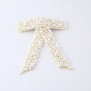 Elegant white pearl bow hair clip featuring dense rhinestone embellishments on a satin base