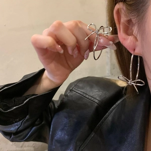 Silver bow knot hoop earrings worn by a model in a trendy and minimalist aesthetic style