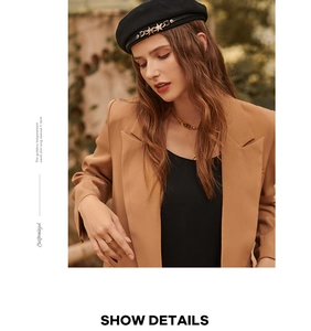 Close-up of a black beret with metal star detail and a chic camel blazer outfit