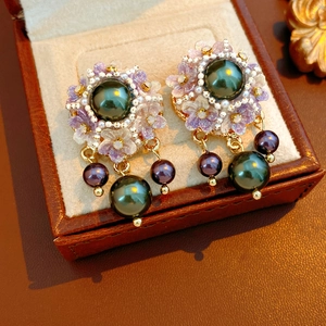 Detailed macro of vintage style pearl tassel earrings with floral resin and gold accents