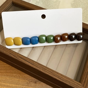 Detailed view of colorful resin square stud earrings set on a white display card