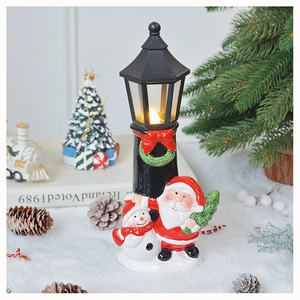 Close-up of lighted Santa and Snowman ceramic street lamp ornament with snowy background