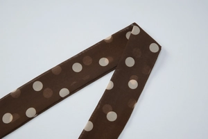 Gros plan sur un tissu en soie marron à pois montrant la texture et les détails du motif