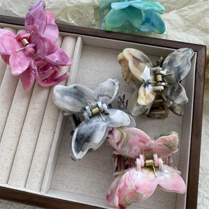 Detail of butterfly hair claws in acetate with marbled texture on a velvet tray