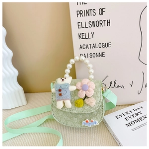 Detail of light green girls' crossbody bag with pearl handle and cartoon bear decor