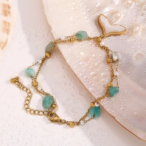Detail of 18K gold double-layer anklet with green stone, pearl, and shell heart charm