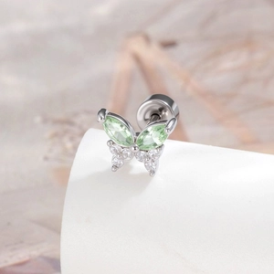 Silver butterfly cartilage earring with green zircon on a minimalist display stand