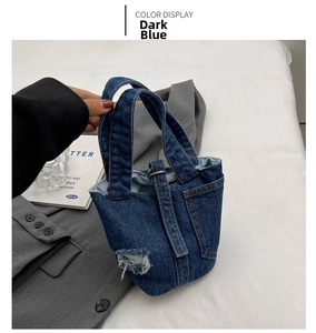 Close-up of dark blue denim tote bag with vintage distressed details and metal hardware