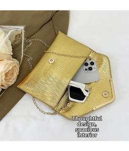 Détails d'un sac enveloppe doré avec chaîne montrant le rangement du mobile et lunettes