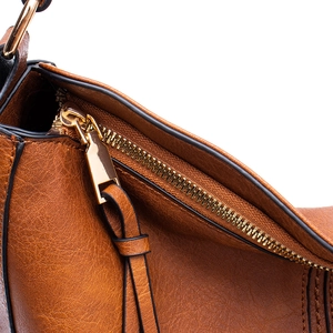 Macro shot of brown pebble leather texture and gold zipper detail on the shoulder bag