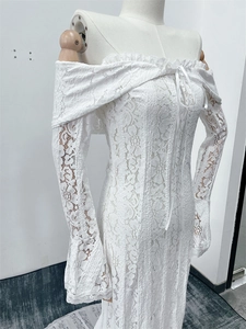 Detail of white lace off-shoulder long dress showing intricate floral crochet texture