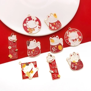 Dettaglio di ciondoli Maneki Neko in smalto rosso e oro per la creazione di gioielli