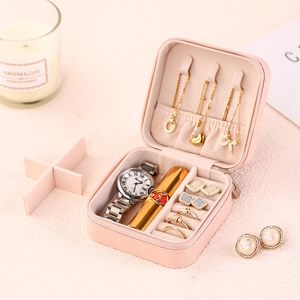 Pink portable travel jewelry organizer box for necklaces and rings in a cozy scene