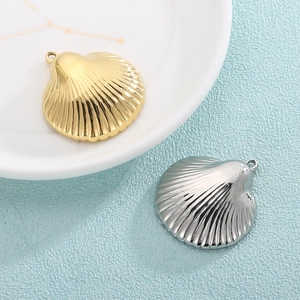 Golden and silver shell-shaped stainless steel pendant charms on a textured background