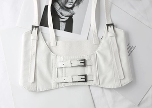 Detail of white faux leather harness belt with lychee texture and black metal buckles