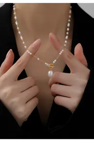 Detailed close-up of Baroque pearl pendant and gold OT buckle on an elegant necklace